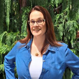 female staff member posing in front of leaves