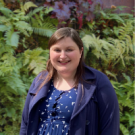 female staff member posing in front of leaves